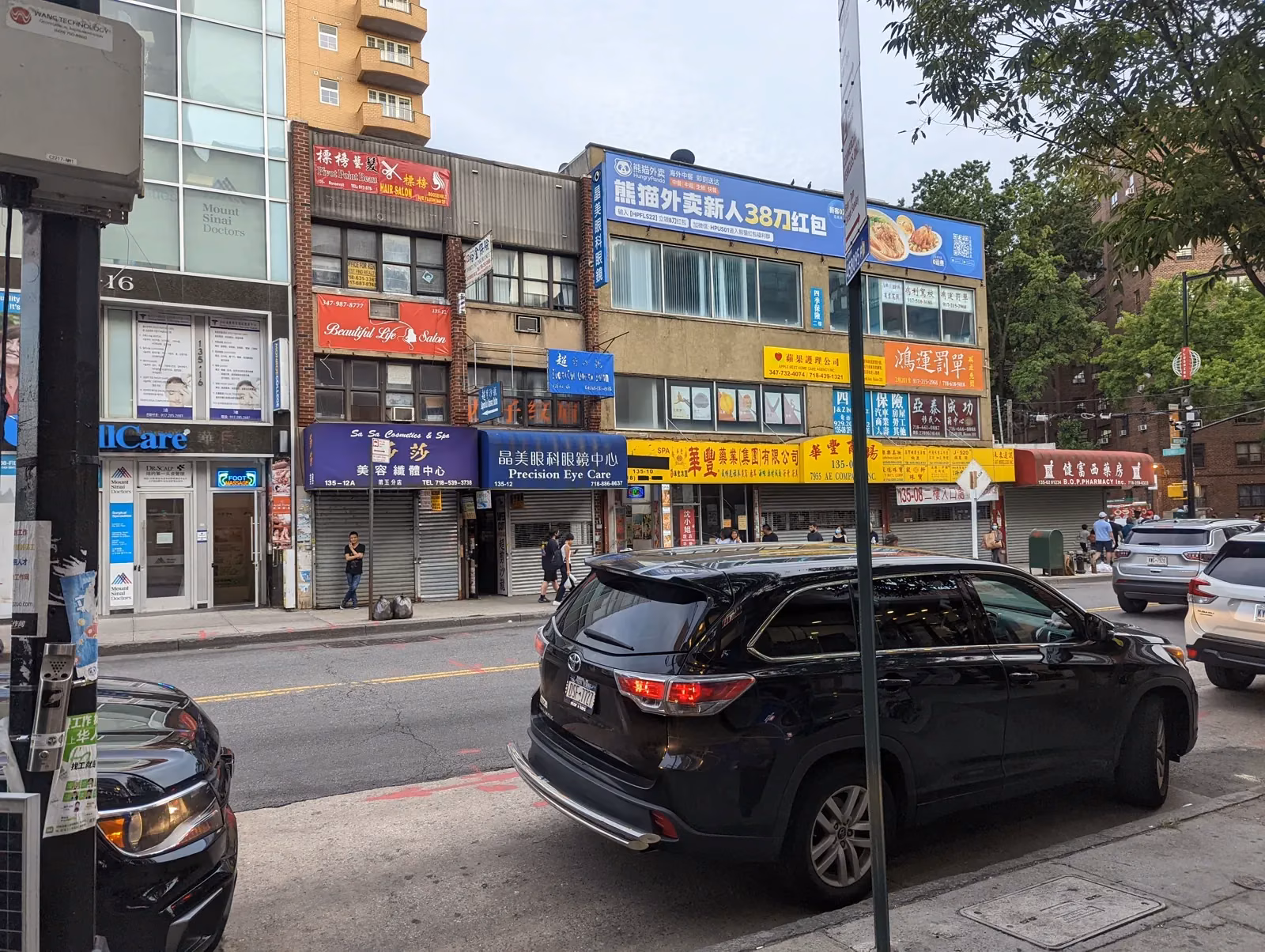 Main Street storefronts in Flushing, signage stacked in Chinese and English