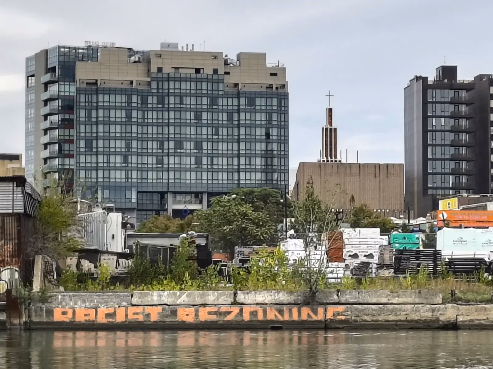 Go to Hard Places — graffiti reading &ldquo;Racist Rezoning&rdquo; across Flushing Creek