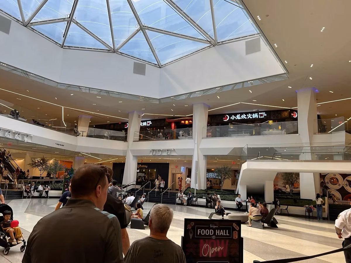 Tangram's skylit atrium with people seated and loitering below the hot-pot signage