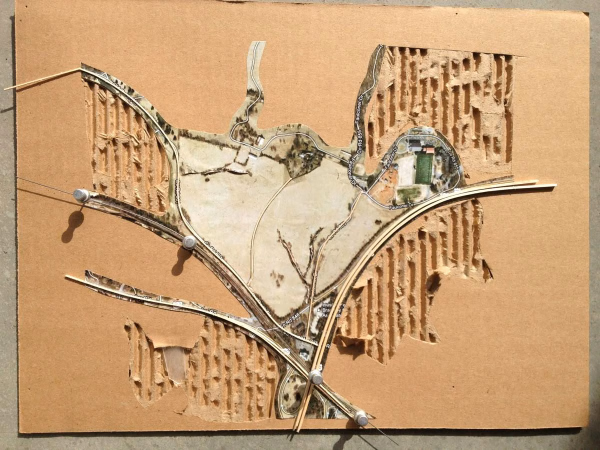 Cardboard site model with cut landform and circulation